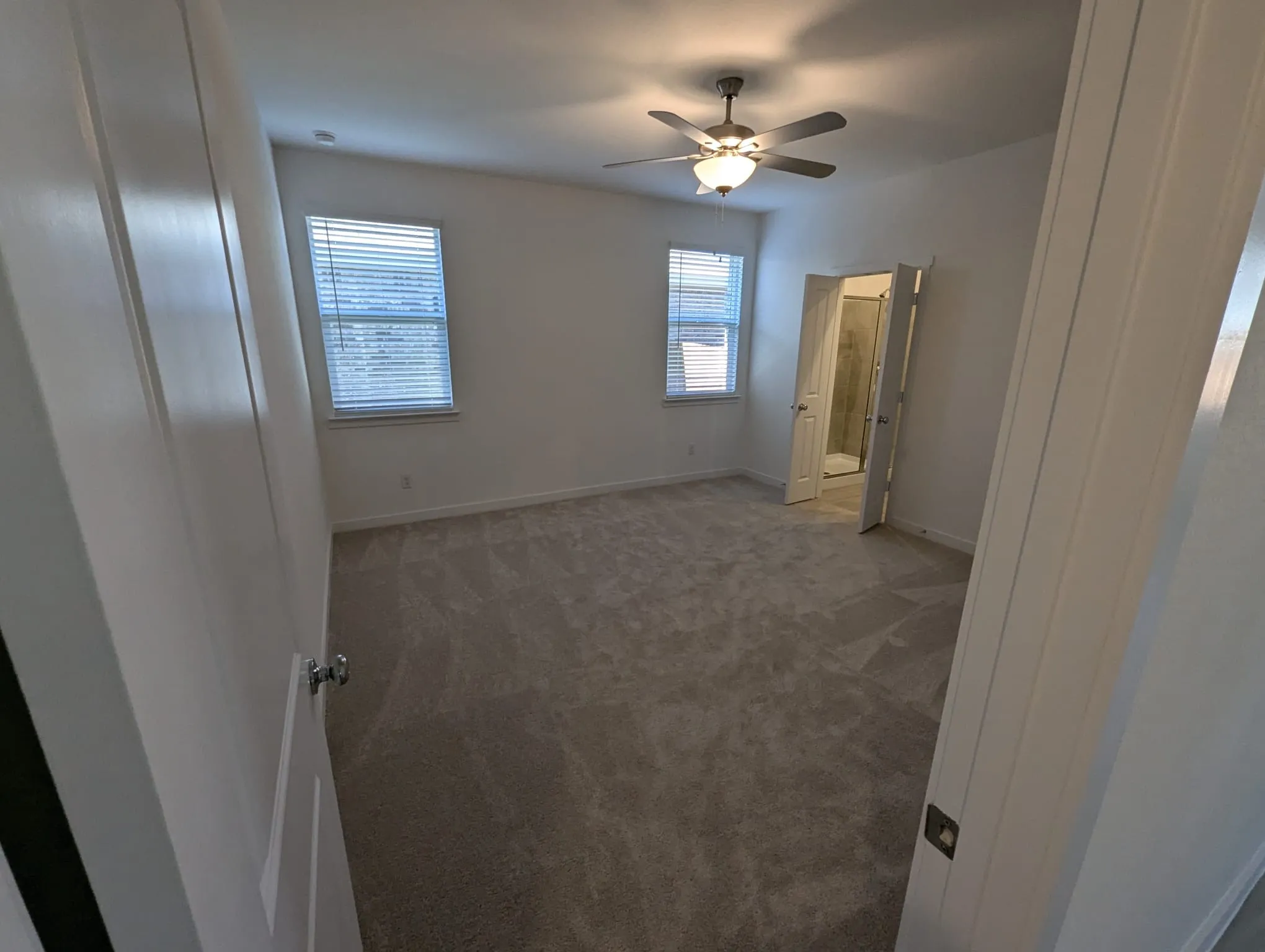 Unfurnished bedroom with ceiling fan and dark colored carpet