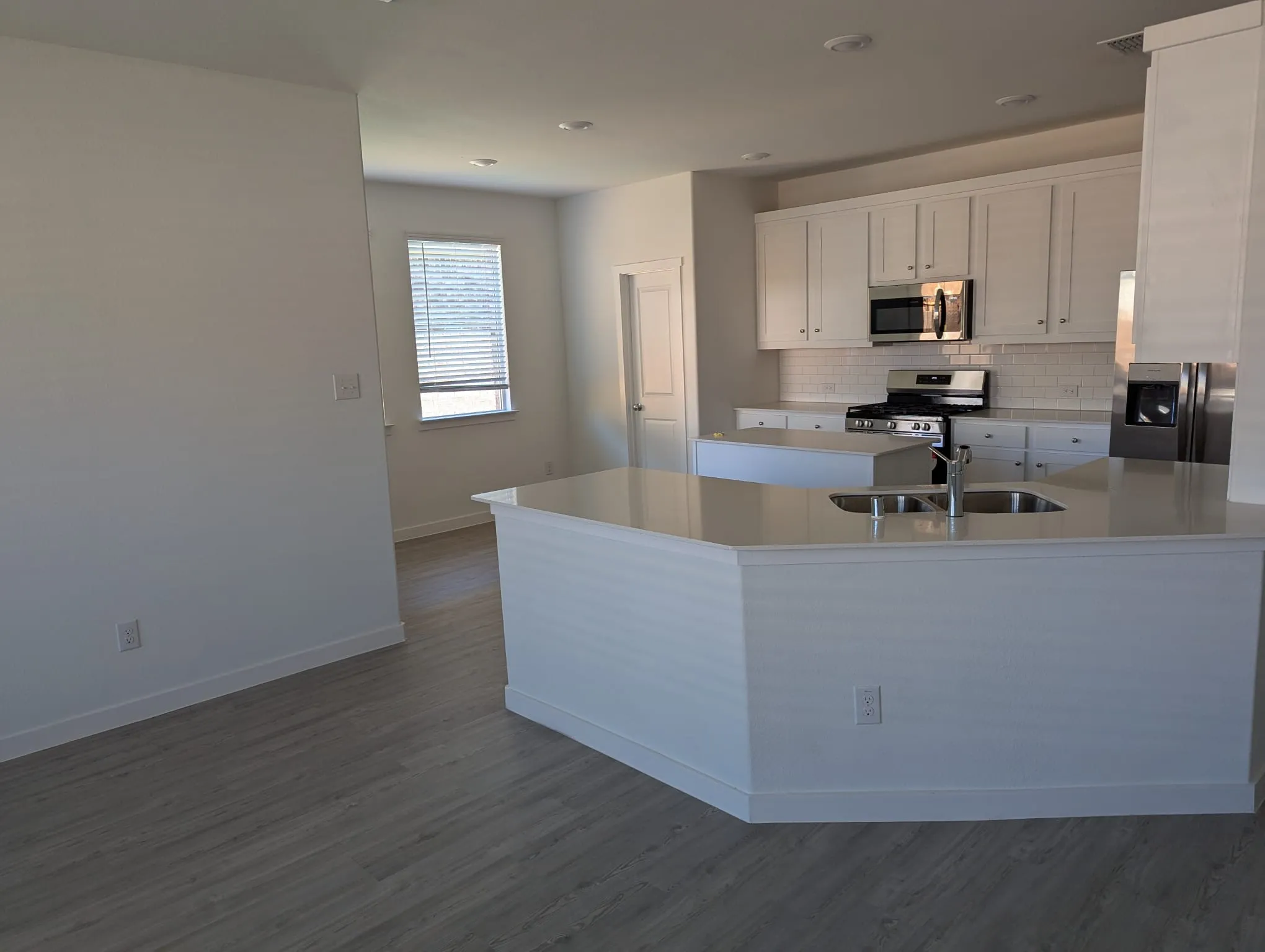 Kitchen with white cabinetry, sink, stainless steel appliances, and hardwood / wood-style flooring