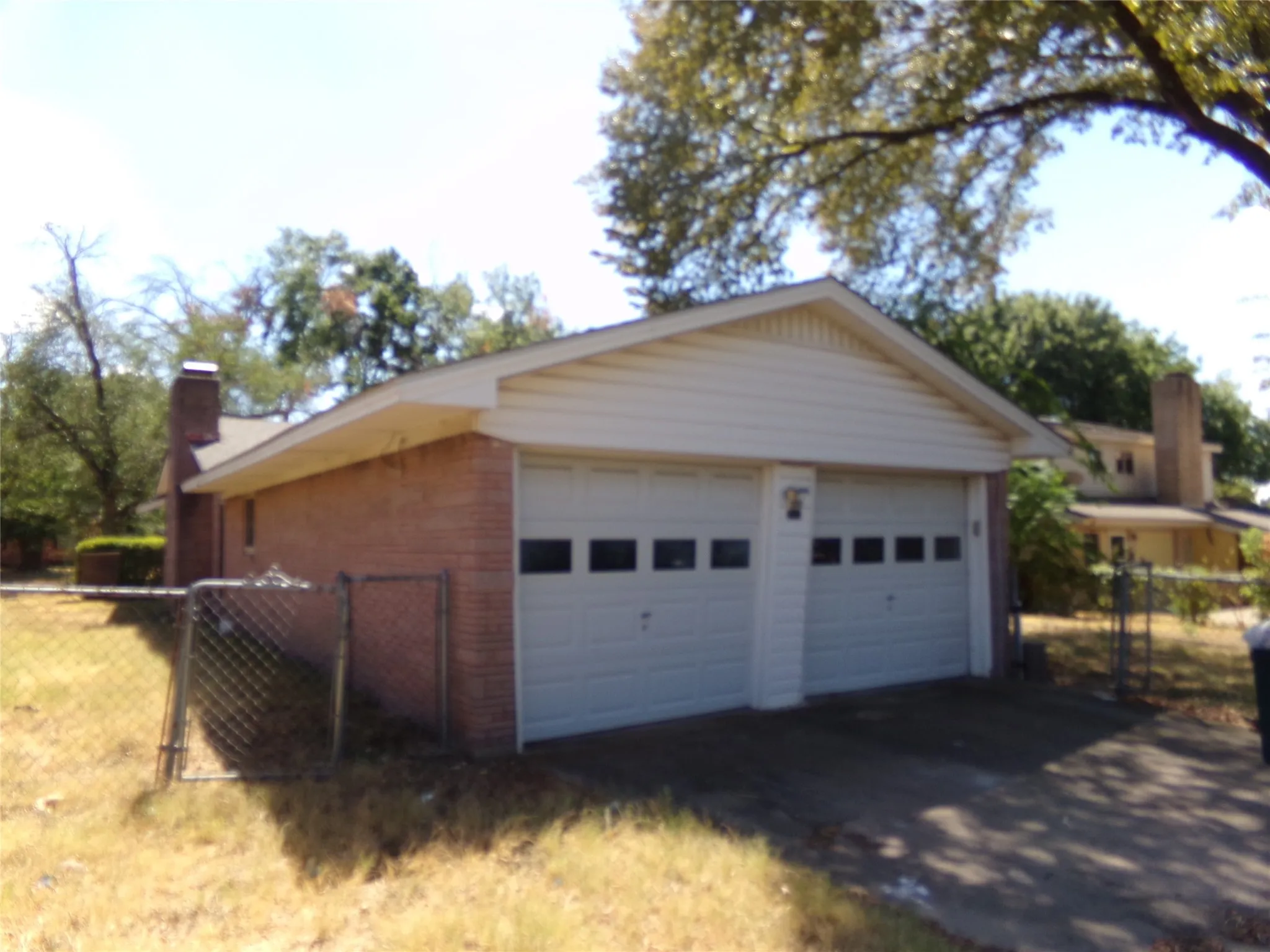 Two-car garage with white paneled doors, brick exterior, and a side chimney