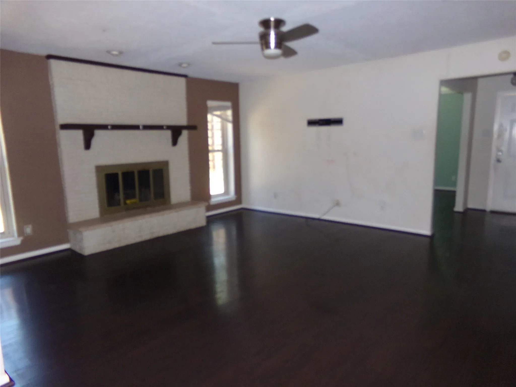 Dark wood-finish flooring, white brick fireplace with hearth, recessed lighting, and ceiling fan