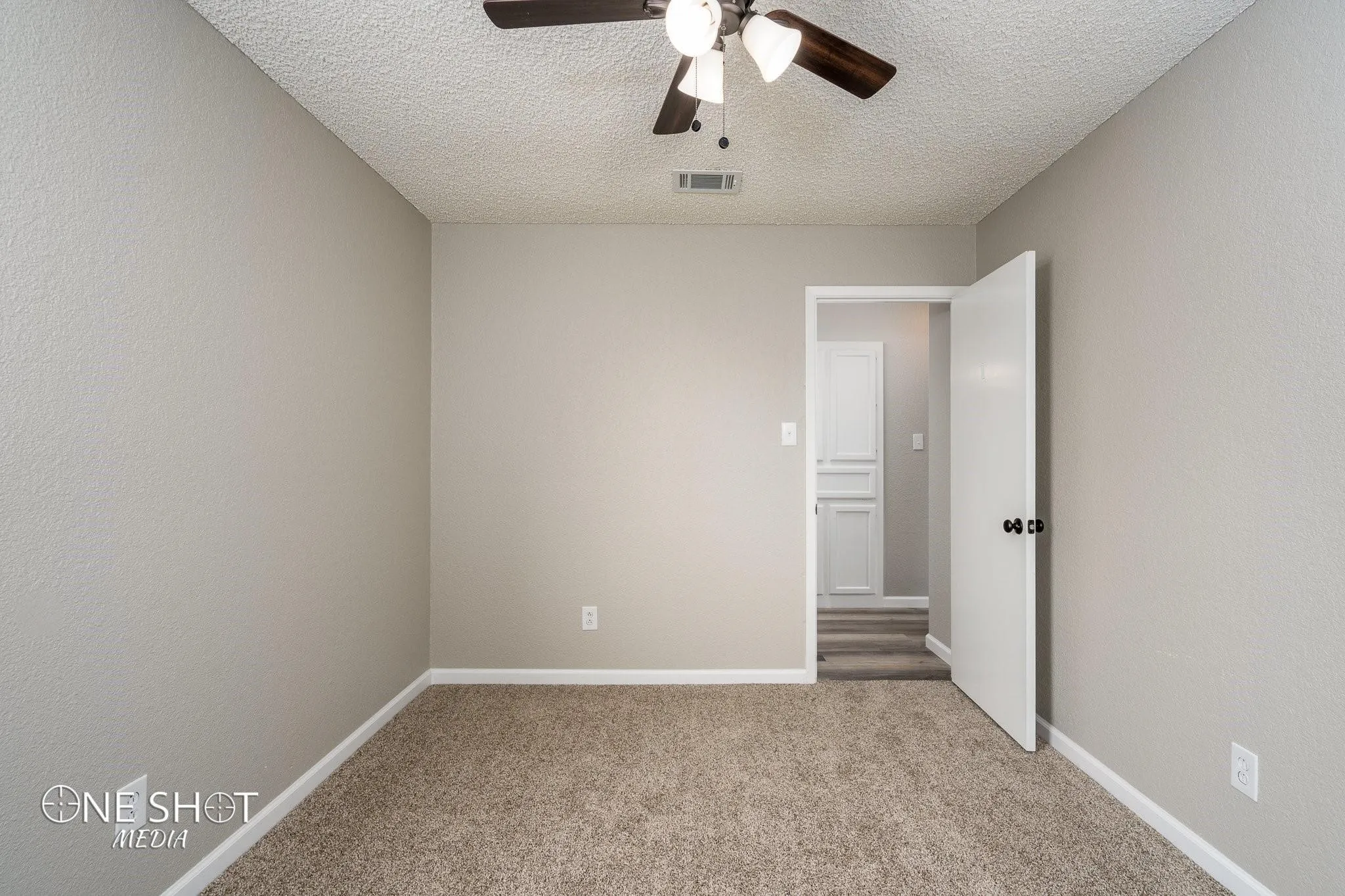 Carpeted empty room featuring a textured ceiling and ceiling fan