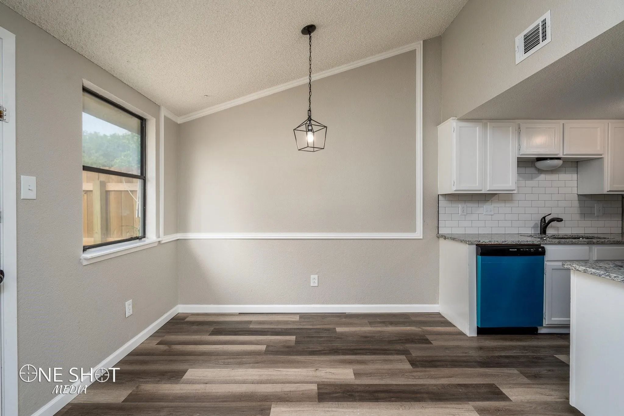 Kitchen featuring hanging light fixtures, crown molding, black dishwasher, lofted ceiling, and dark wood-type flooring