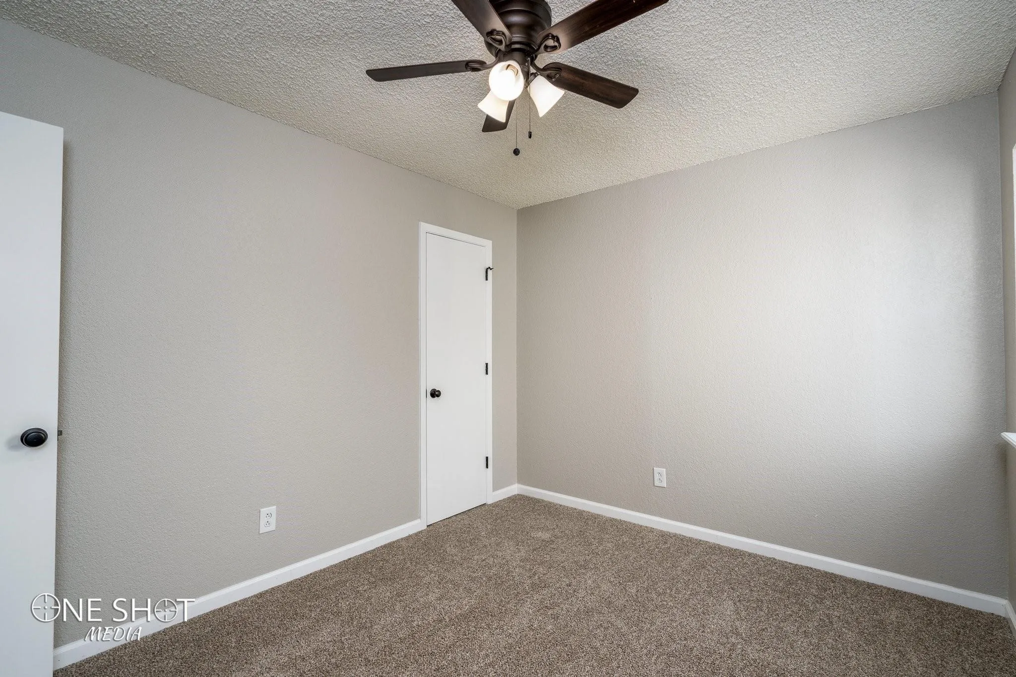 Carpeted spare room with a textured ceiling and ceiling fan