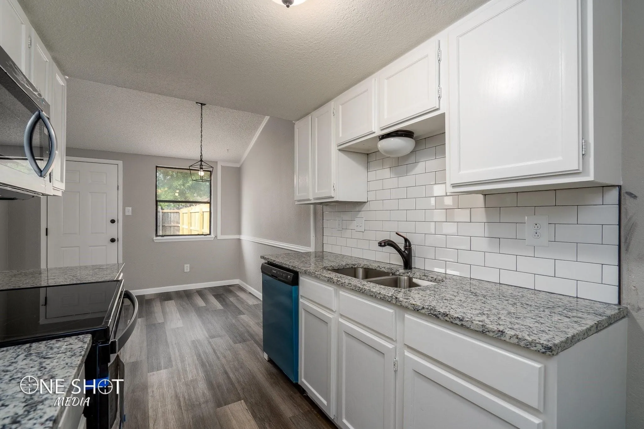 Kitchen featuring white cabinets, sink, black dishwasher, backsplash, and dark wood-type flooring