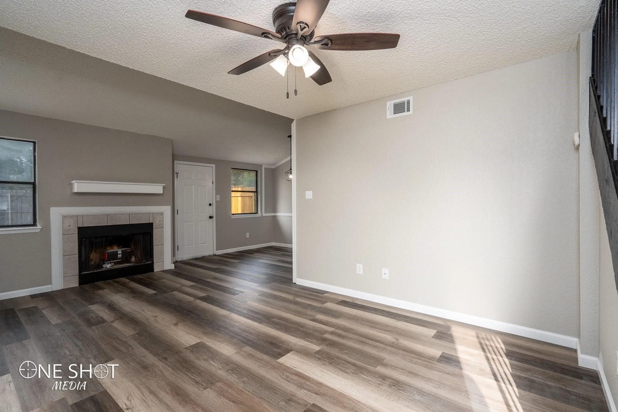Unfurnished living room with ceiling fan, a tiled fireplace, a textured ceiling, and hardwood / wood-style flooring