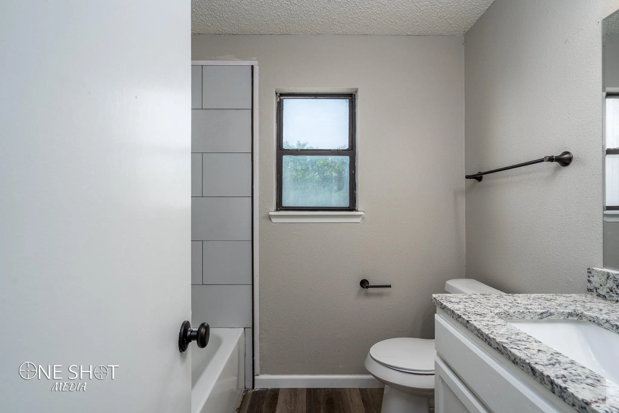 Full bathroom with a textured ceiling, vanity, wood-type flooring, and toilet