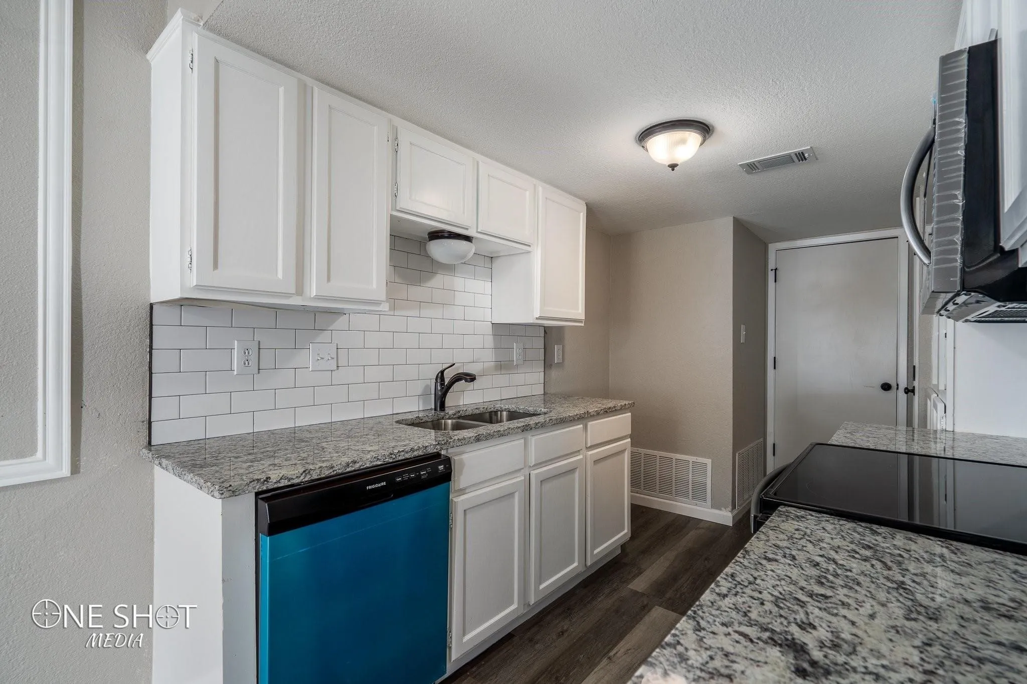 Kitchen featuring dishwashing machine, white cabinets, decorative backsplash, sink, and dark wood-type flooring