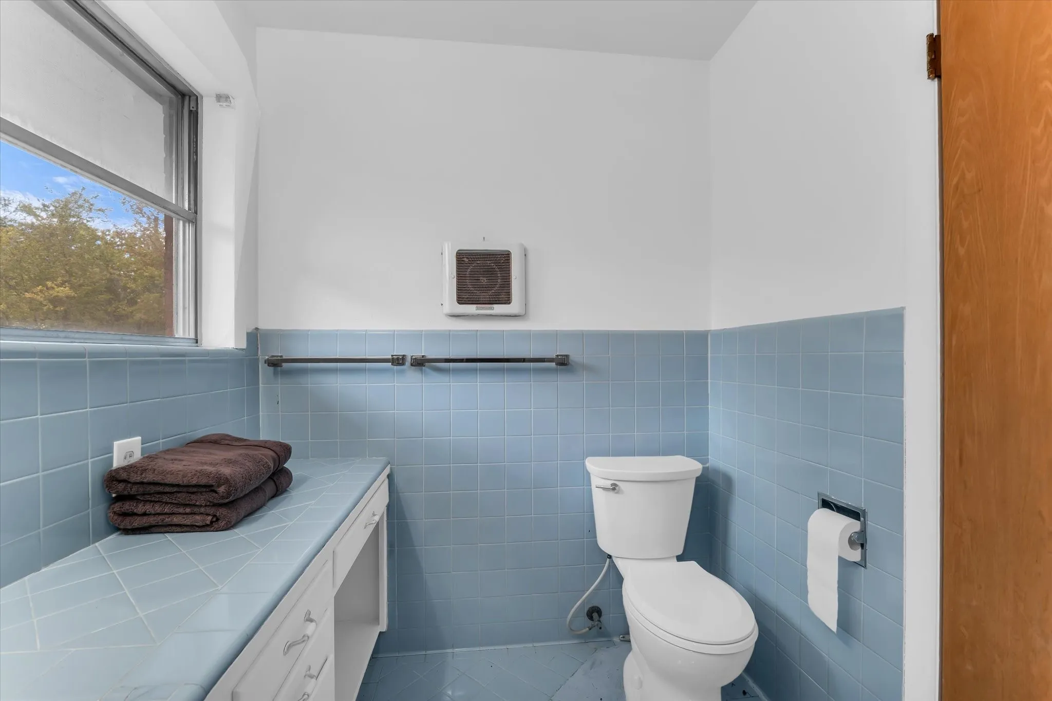 Primary bath features beautiful natural lighting, built-in storage, and charming original tile.