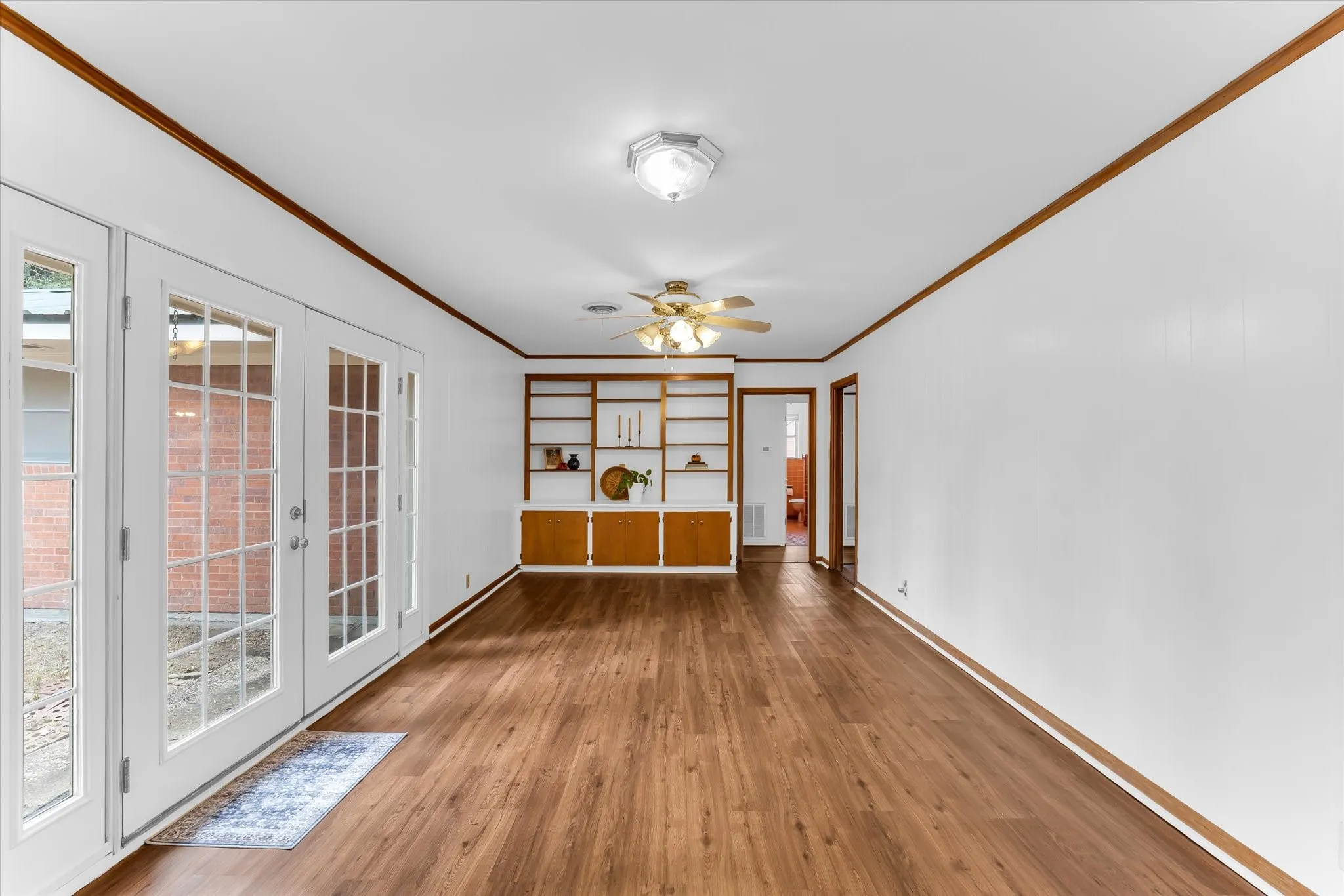 The family room as seen from the kitchen. The family room features French doors, built-in cabinetry, and low maintenance hard flooring.