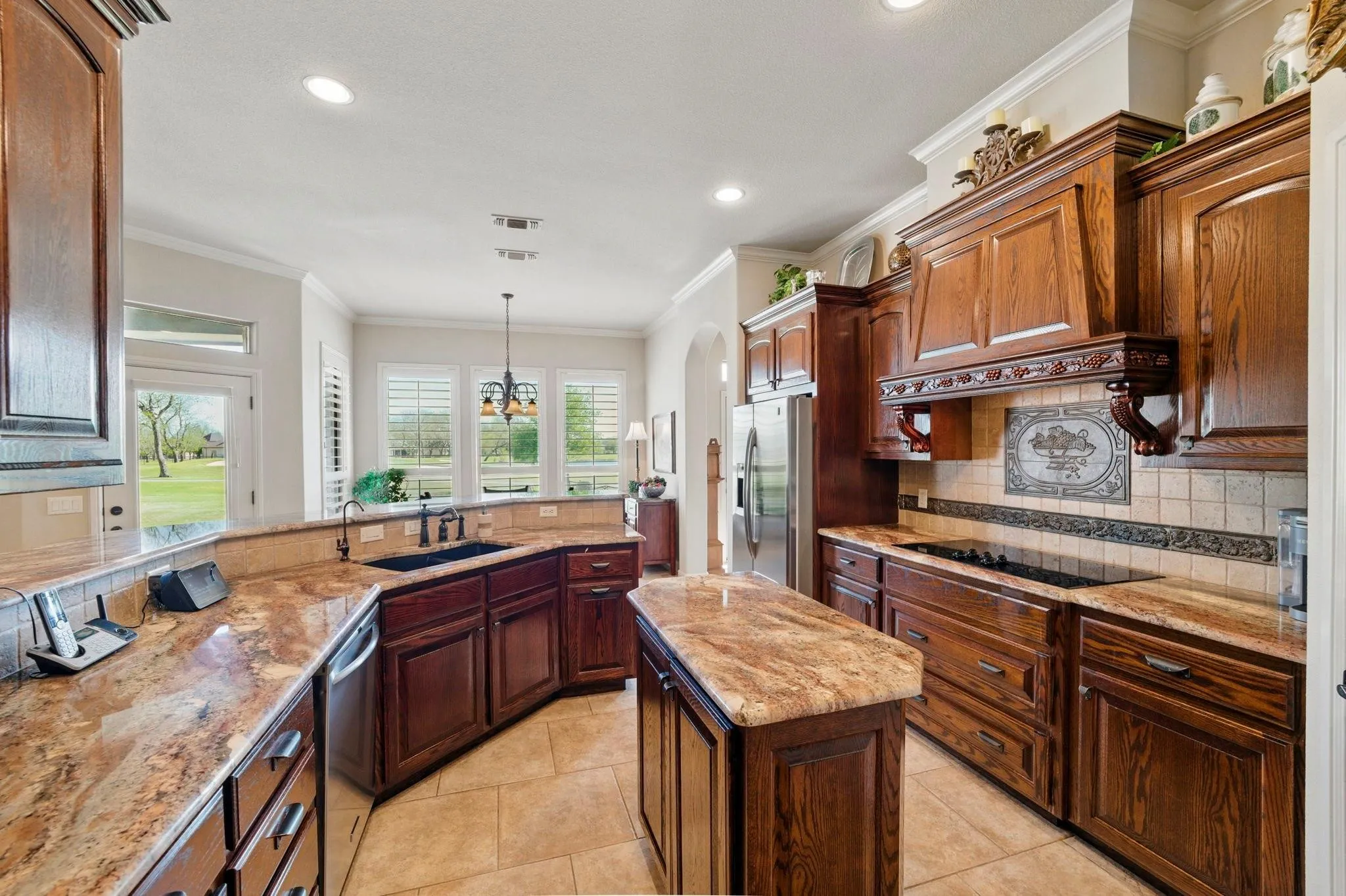 Rich wood cabinetry and a central island with natural stone countertops