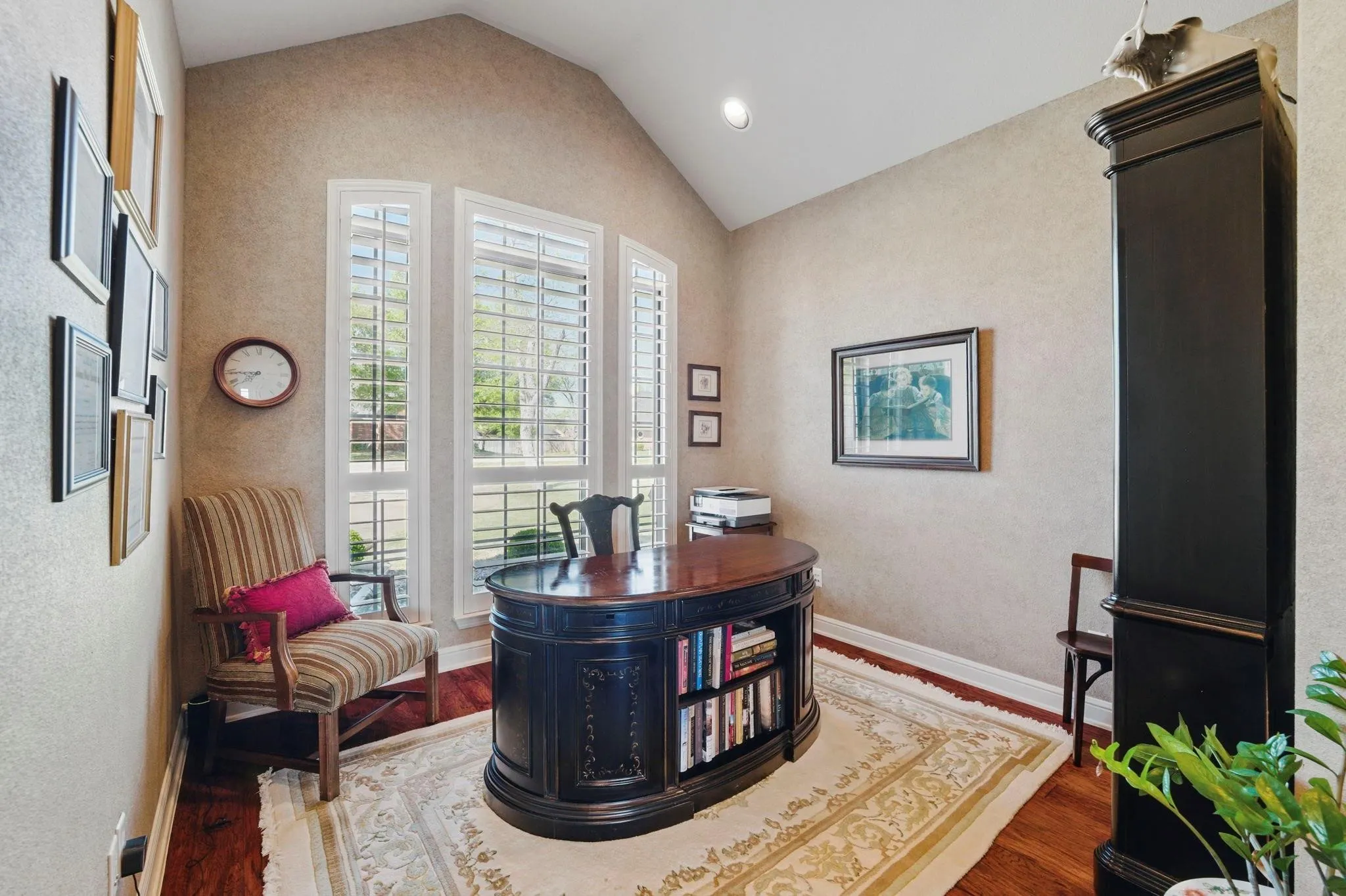 Vaulted ceiling with recessed lighting, rich wood-finish flooring, and multiple tall windows with plantation shutters