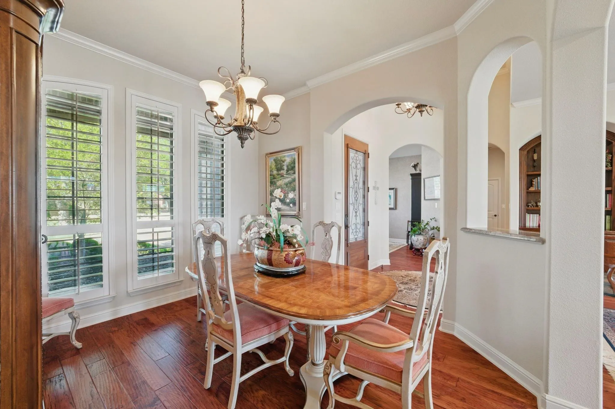 Wood-finish flooring, multiple arched doorways, crown molding, and a decorative​​‌​​​​‌​​‌‌​‌‌​​​‌‌​‌​‌​‌​​​‌​​ chandelier