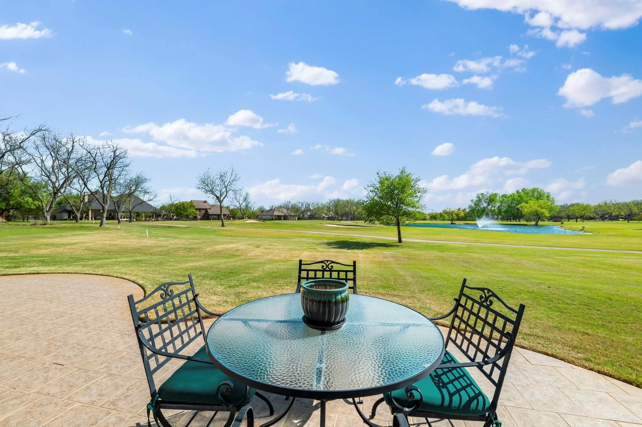 Expansive backyard with a manicured lawn, a large pond featuring a fountain, and mature trees