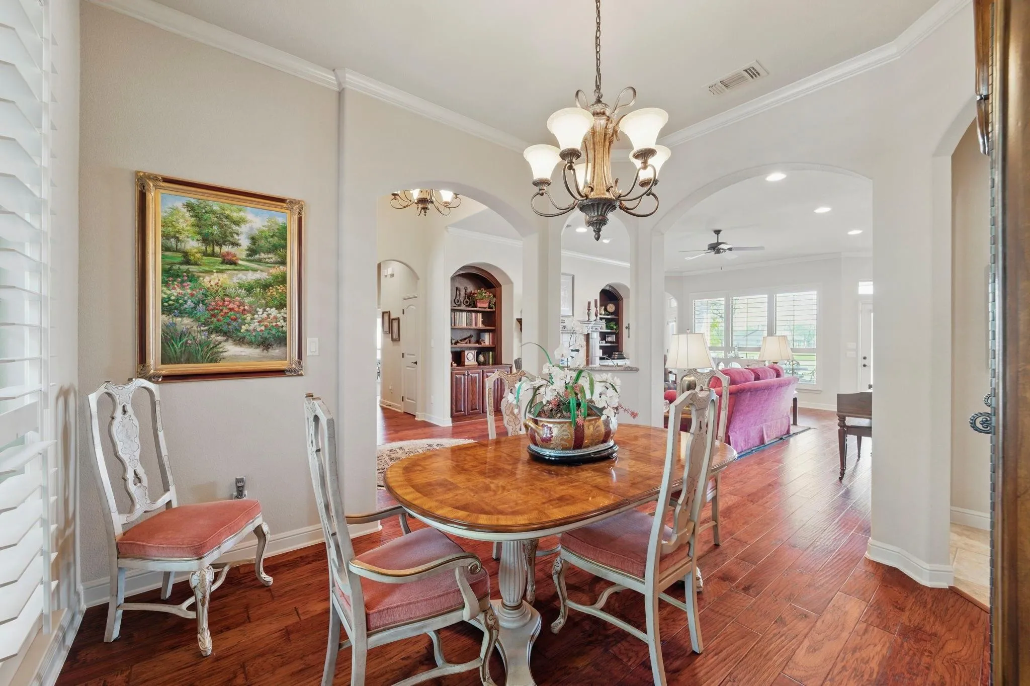 Wood-finish flooring, recessed lighting, arched doorways, crown molding, and a chandelier with glass shades