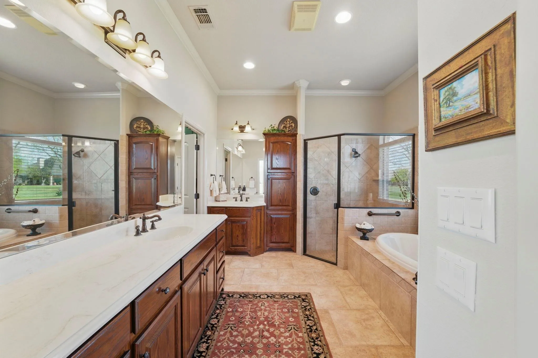 Dual vanity with an expansive countertop, wood-finish cabinetry, a separate walk-in shower with glass enclosure, a built-in soaking tub, and tile flooring