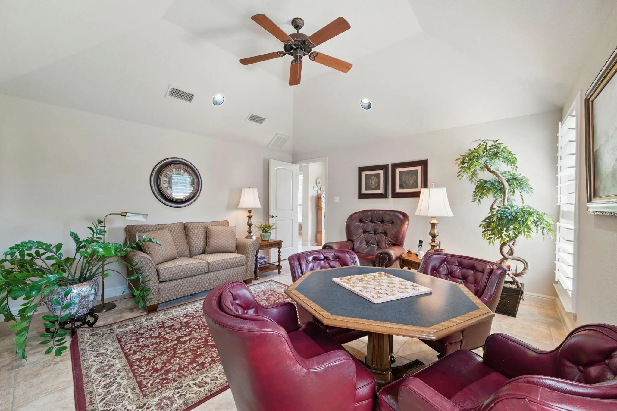 Recessed lighting, ceiling fan, vaulted ceiling, plantation shutters, and tile flooring