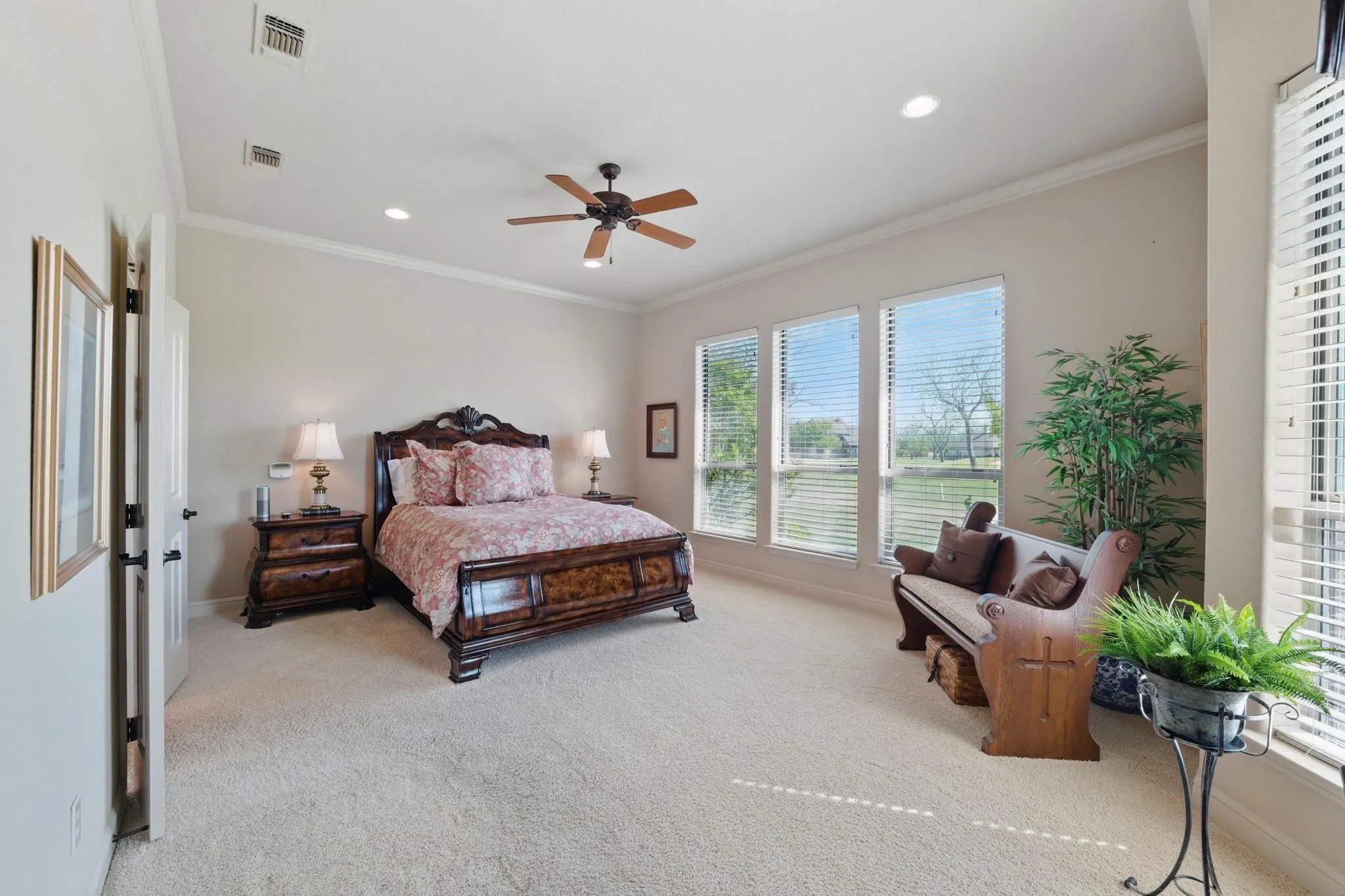 Spacious room featuring carpeting, three large windows with blinds, recessed lighting, and a ceiling fan