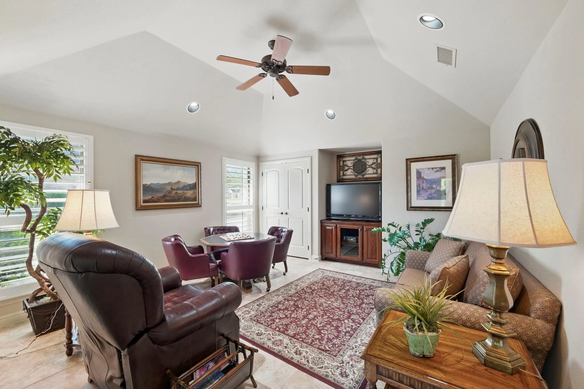 Vaulted ceiling with a ceiling fan, recessed lighting, plantation shutters, and a built-in media cabinet
