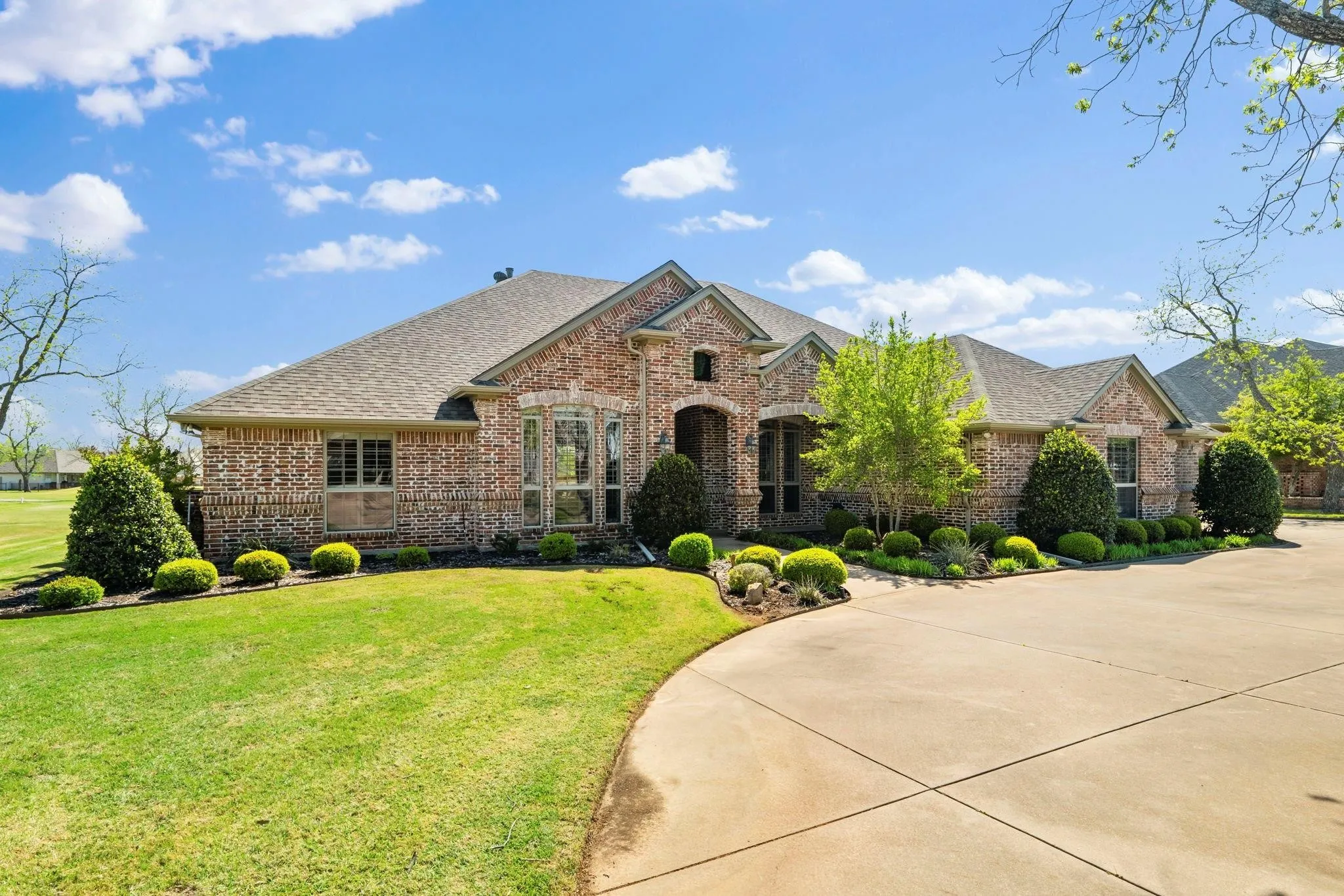 Brick facade, pitched roof, arched entry, bay window, landscaped foundation plantings