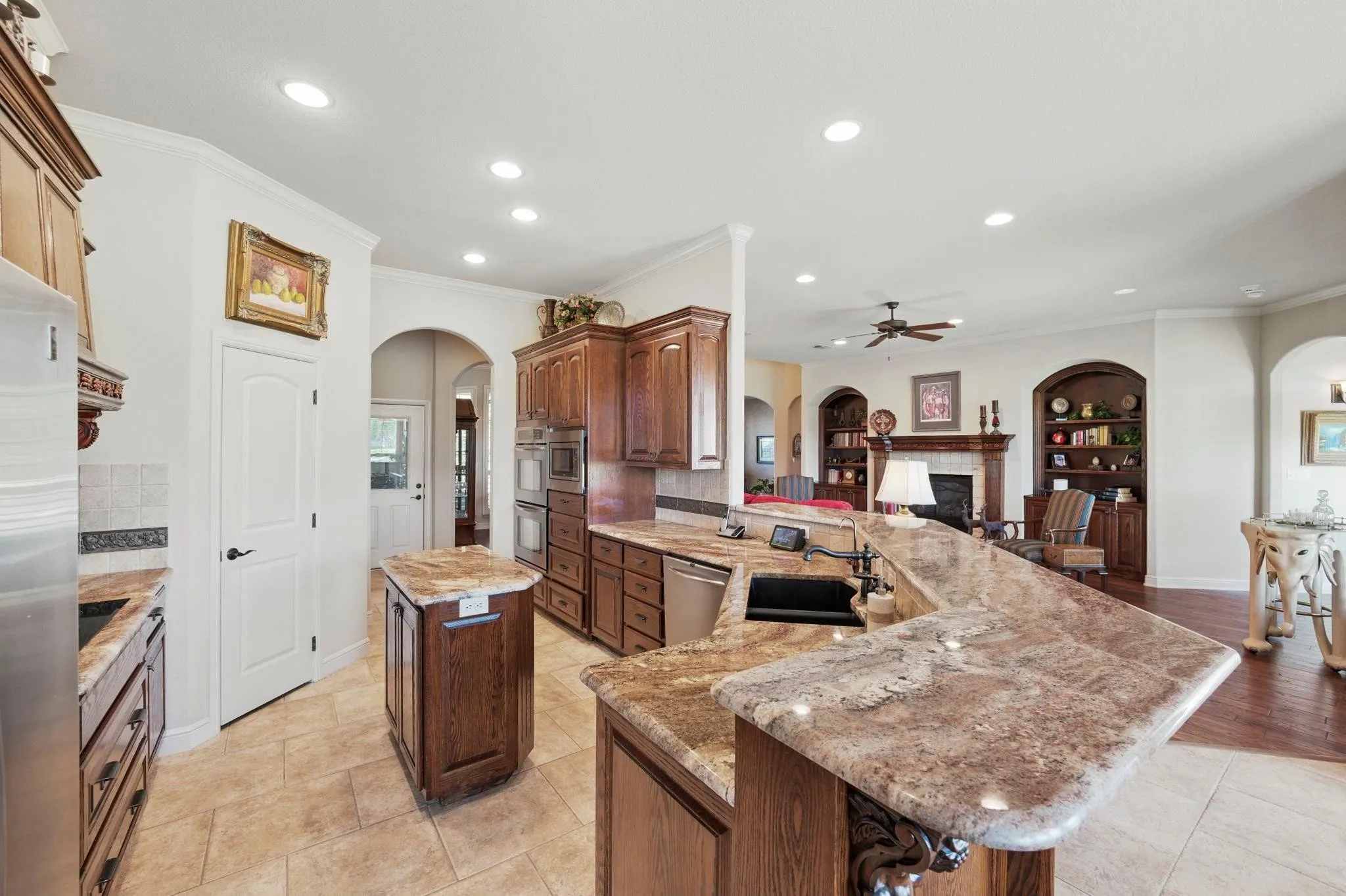 Kitchen featuring recessed lighting, tile flooring, wood cabinetry, stone countertops, and stainless steel appliances