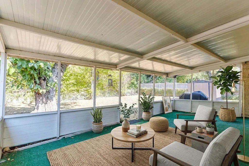Screened-in porch featuring a paneled ceiling, expansive window panels, and a green floor covering