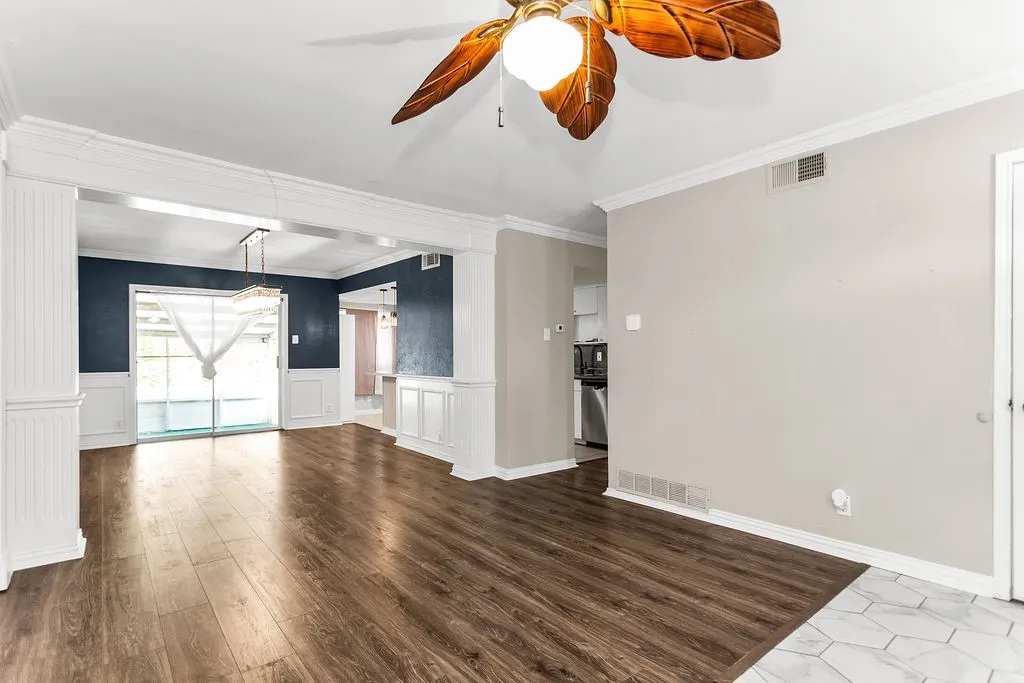 Wood-finish flooring, white trim details, ceiling fan, sliding glass door, kitchen visibility