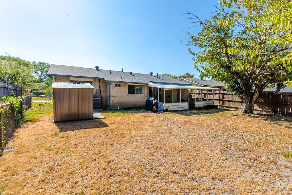 Expansive backyard featuring a mature shade tree, privacy fencing, and a detached storage shed