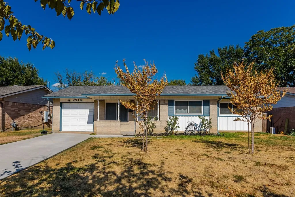 Brick and siding exterior with blue window shutters, attached garage, and concrete driveway