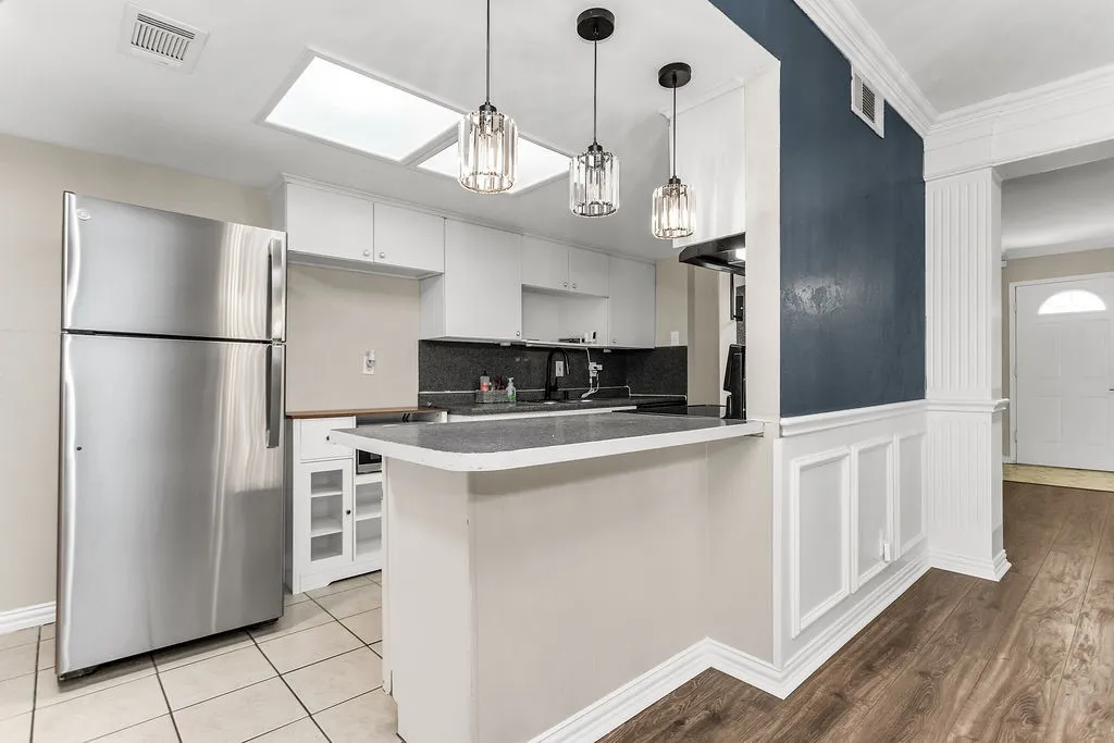 Kitchen featuring white cabinetry, a skylight, a breakfast bar with dark countertops, and stainless steel appliances