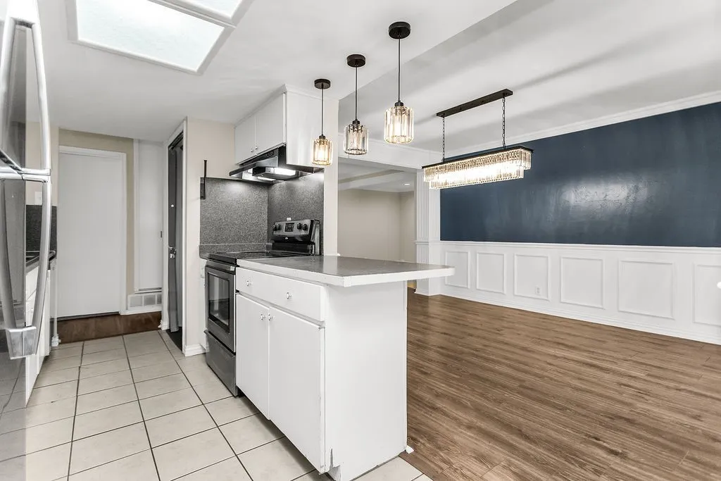 Kitchen featuring a skylight, white cabinetry, and stainless steel refrigerator