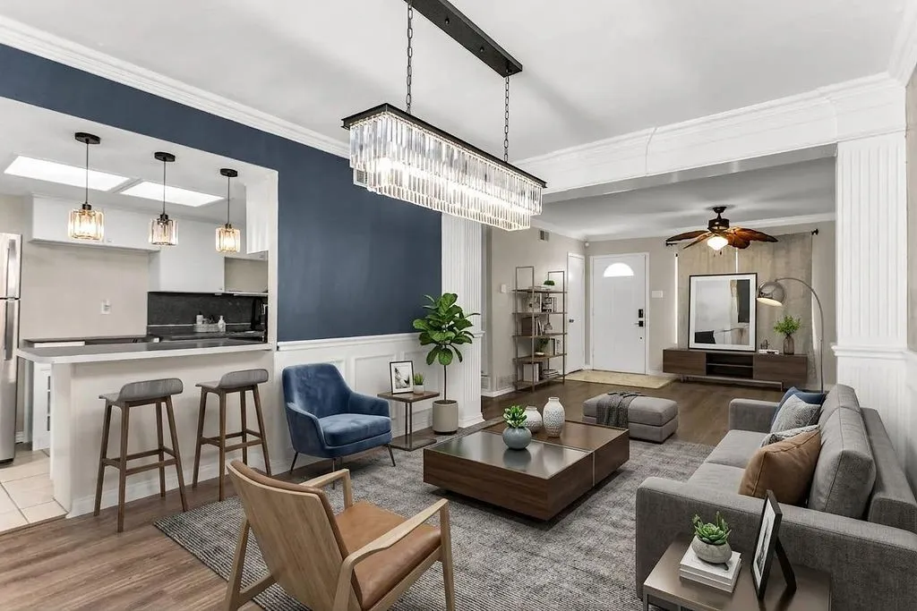 Open-concept living area with wood-finish flooring, a contemporary linear chandelier, and a breakfast bar with pendant lighting