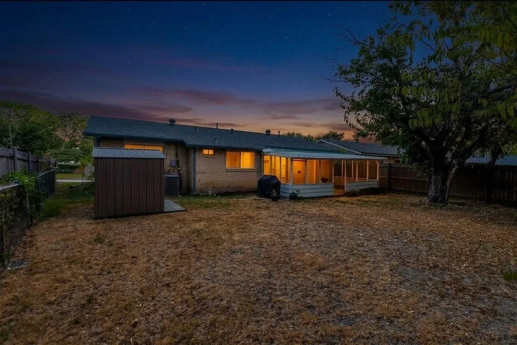 Expansive backyard featuring a screened-in porch, mature tree, and a storage shed
