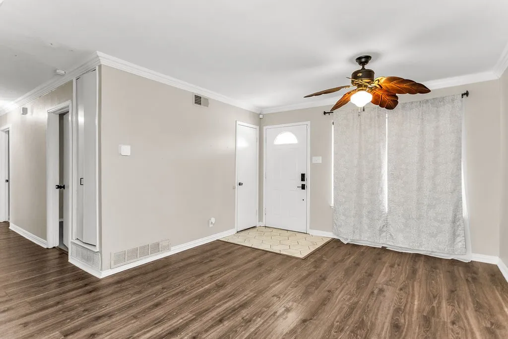 Wood-finish flooring, crown molding, and a ceiling fan with integrated lighting