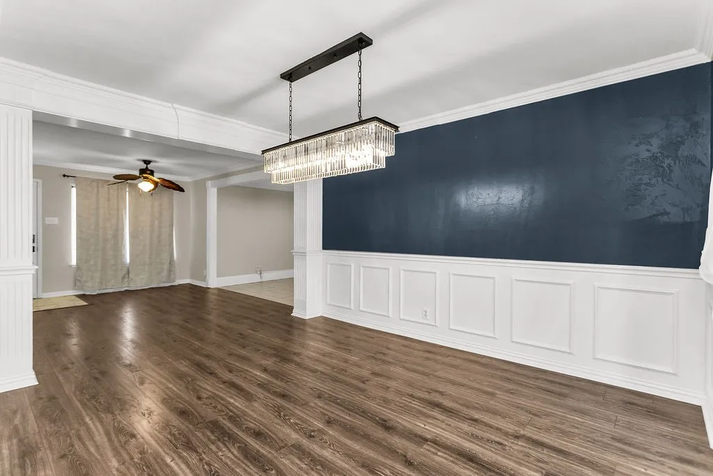 Wood-finish flooring, wainscoting, crown molding, and a crystal chandelier