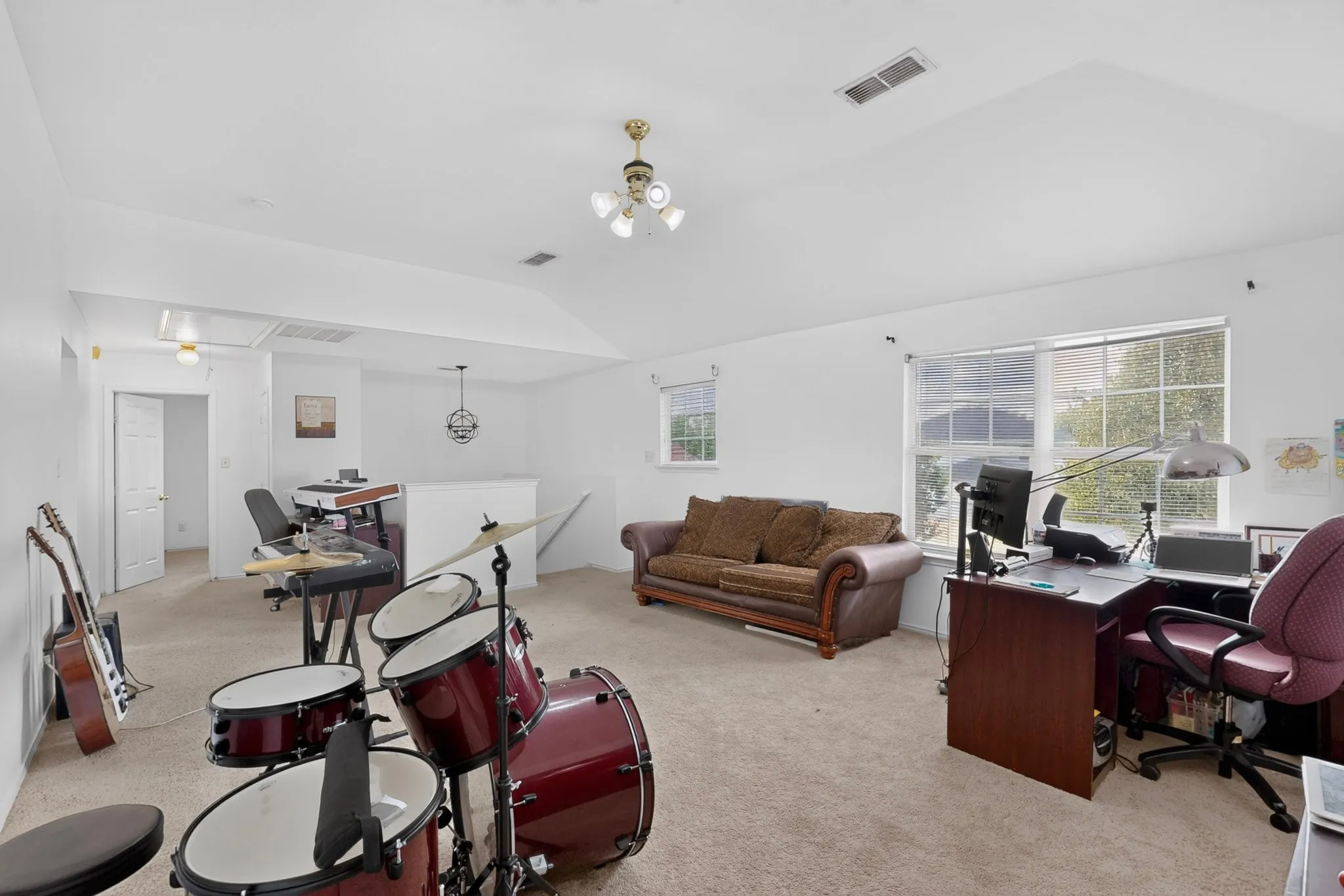 Spacious room featuring vaulted ceilings, neutral carpeting, and multiple windows
