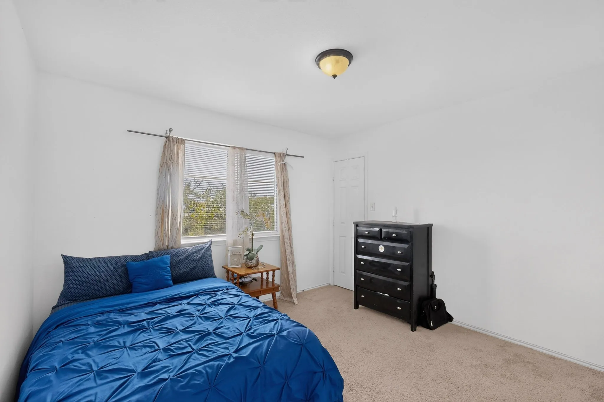 Carpeted flooring, white painted walls, and a single window with blinds