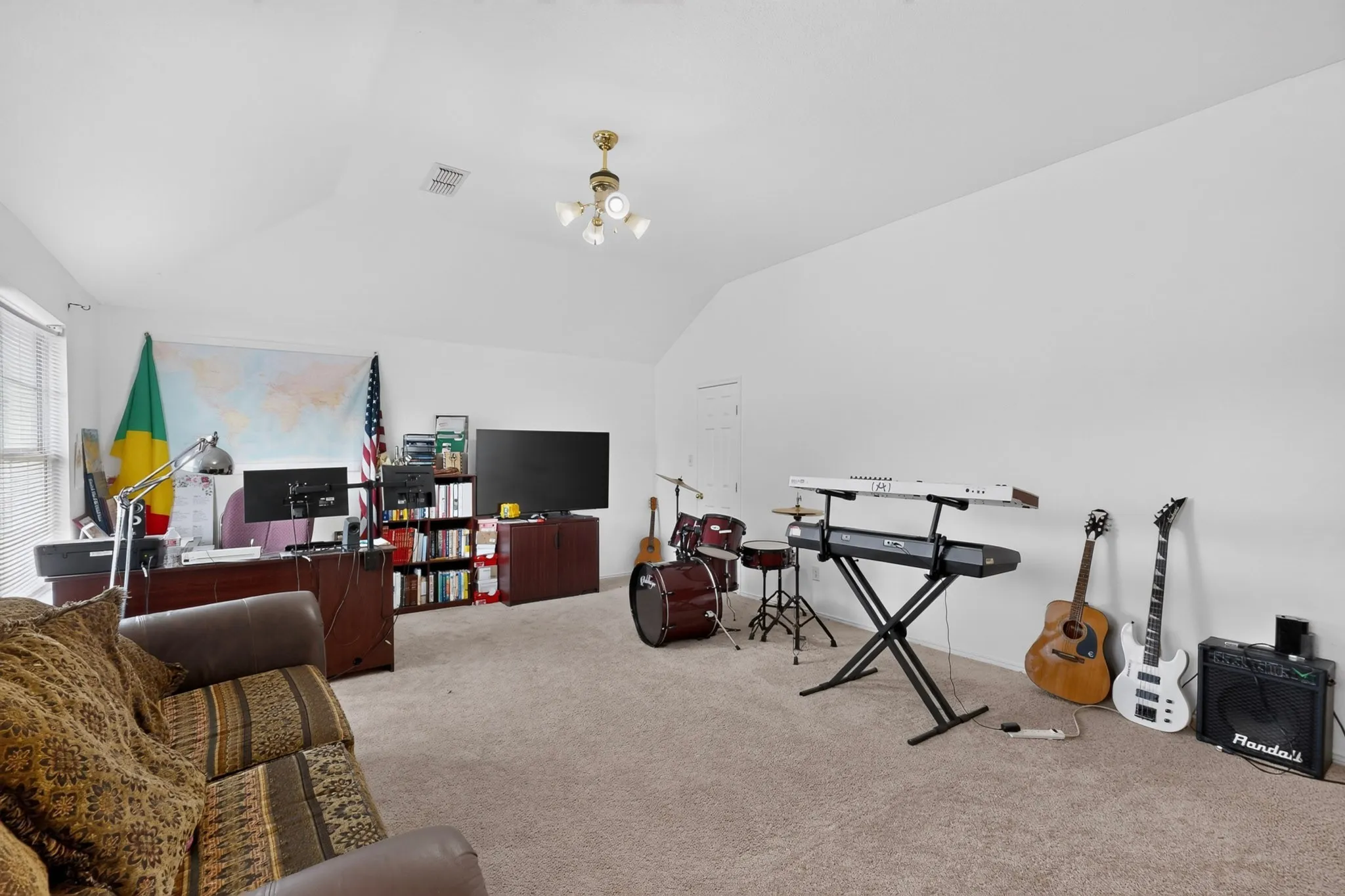 Spacious room featuring vaulted ceilings, neutral carpet, and a window with blinds