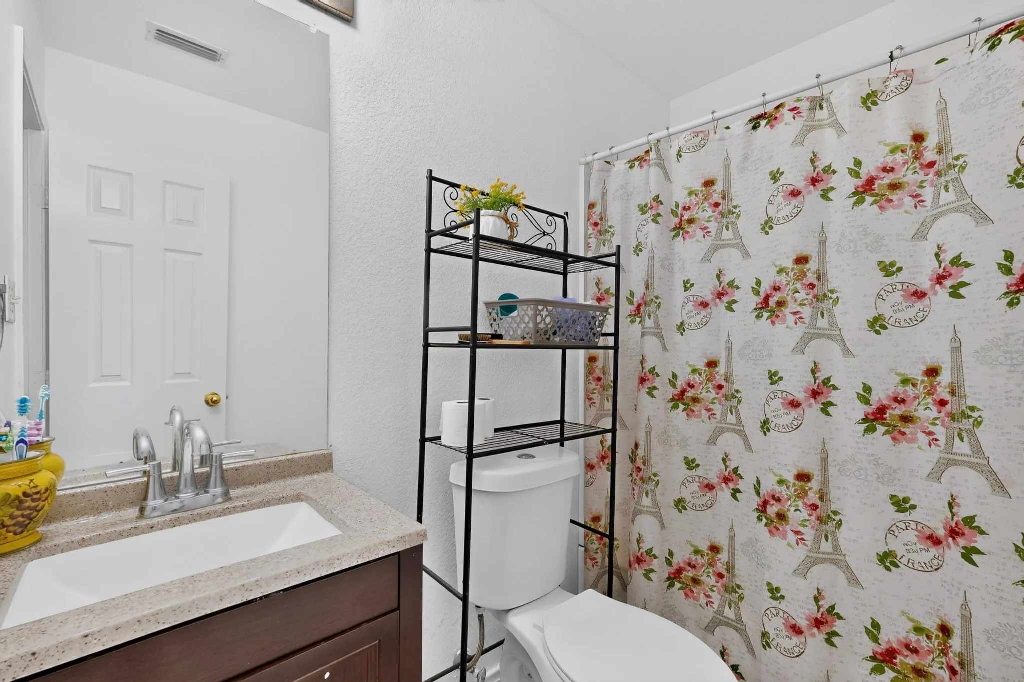 Single vanity with an integrated sink, polished chrome faucet, and a wall-mounted mirror