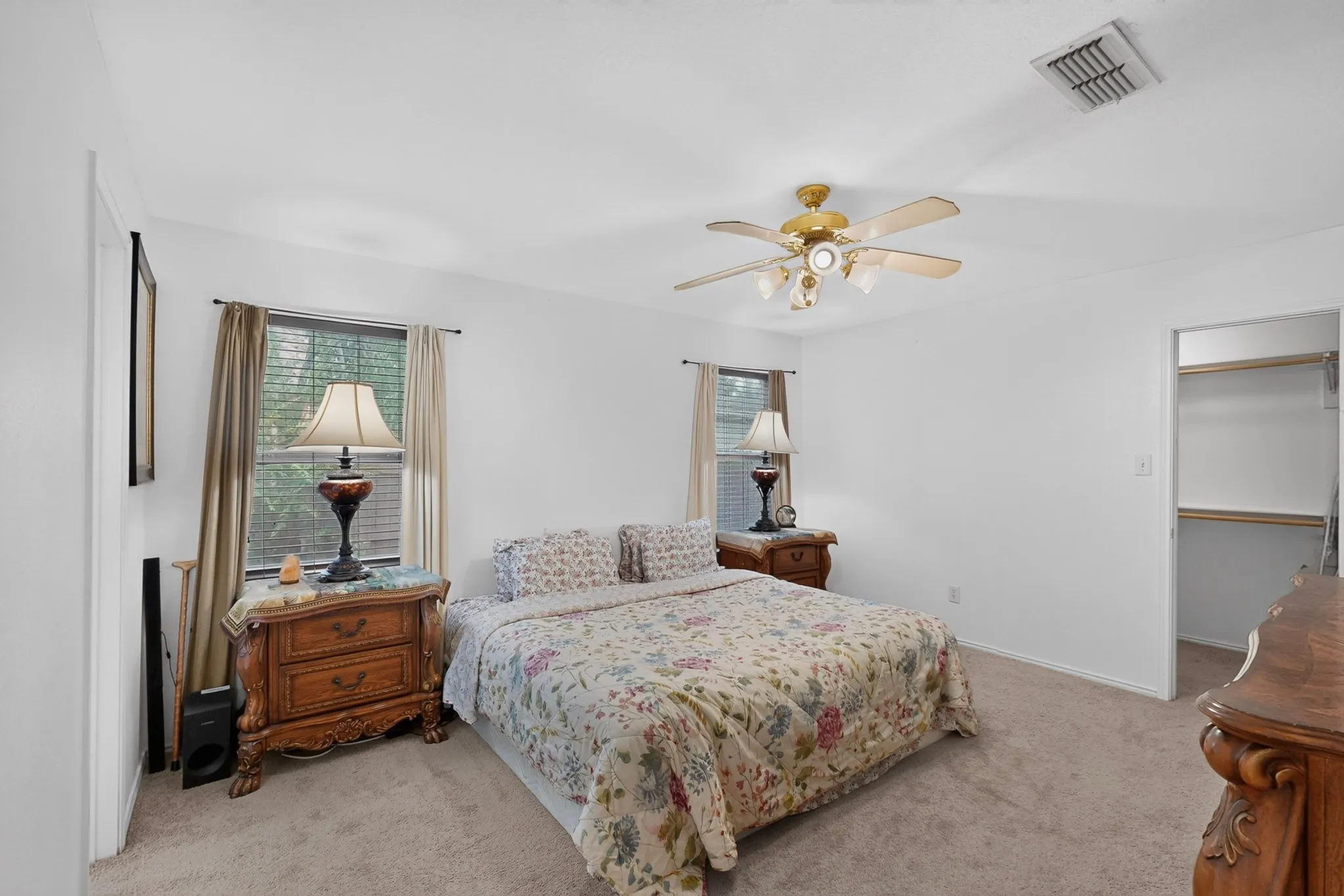 Carpeted flooring, ceiling fan with light fixture, window with blinds, and a built-in closet with shelving