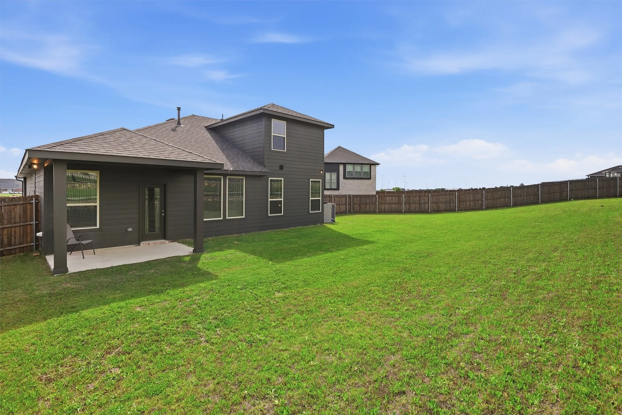 Step outside to an expansive, lush green lawn and a deep covered patio that's perfect for summer BBQs and outdoor lounging. The modern dark siding offers a sophisticated look, while the full privacy fence ensures a secure and serene space for pets and play.