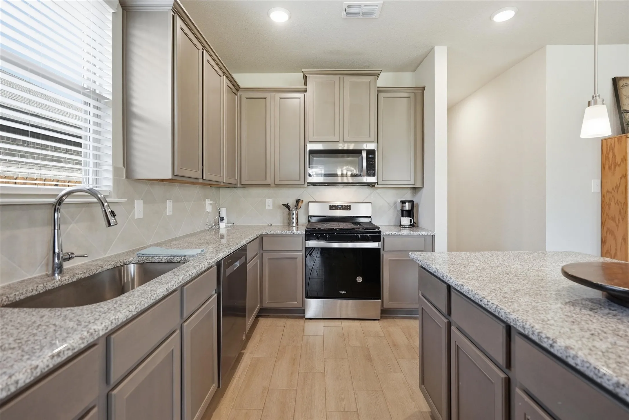 This chef's corner features a powerful range and an integrated microwave, keeping the counters clear for meal prep and entertaining. The sleek, streamlined design and neutral tones provide a timeless look that fits any decor style.