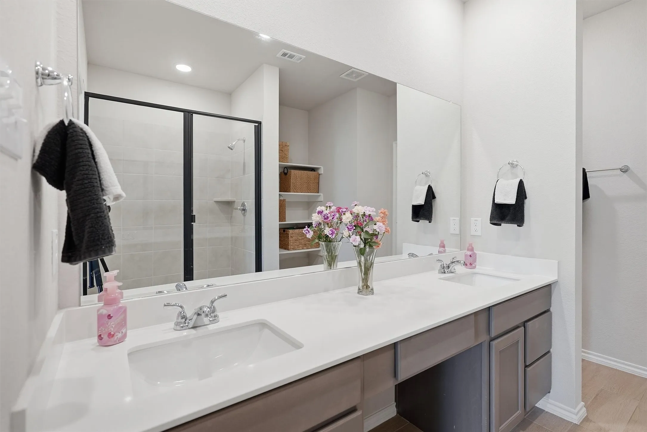 Organization is effortless with an abundance of cabinetry and built-in linen shelving tucked in perfectly into the layout. This spacious vanity offers plenty of room for two, while the recessed lighting ensures a bright and functional space.