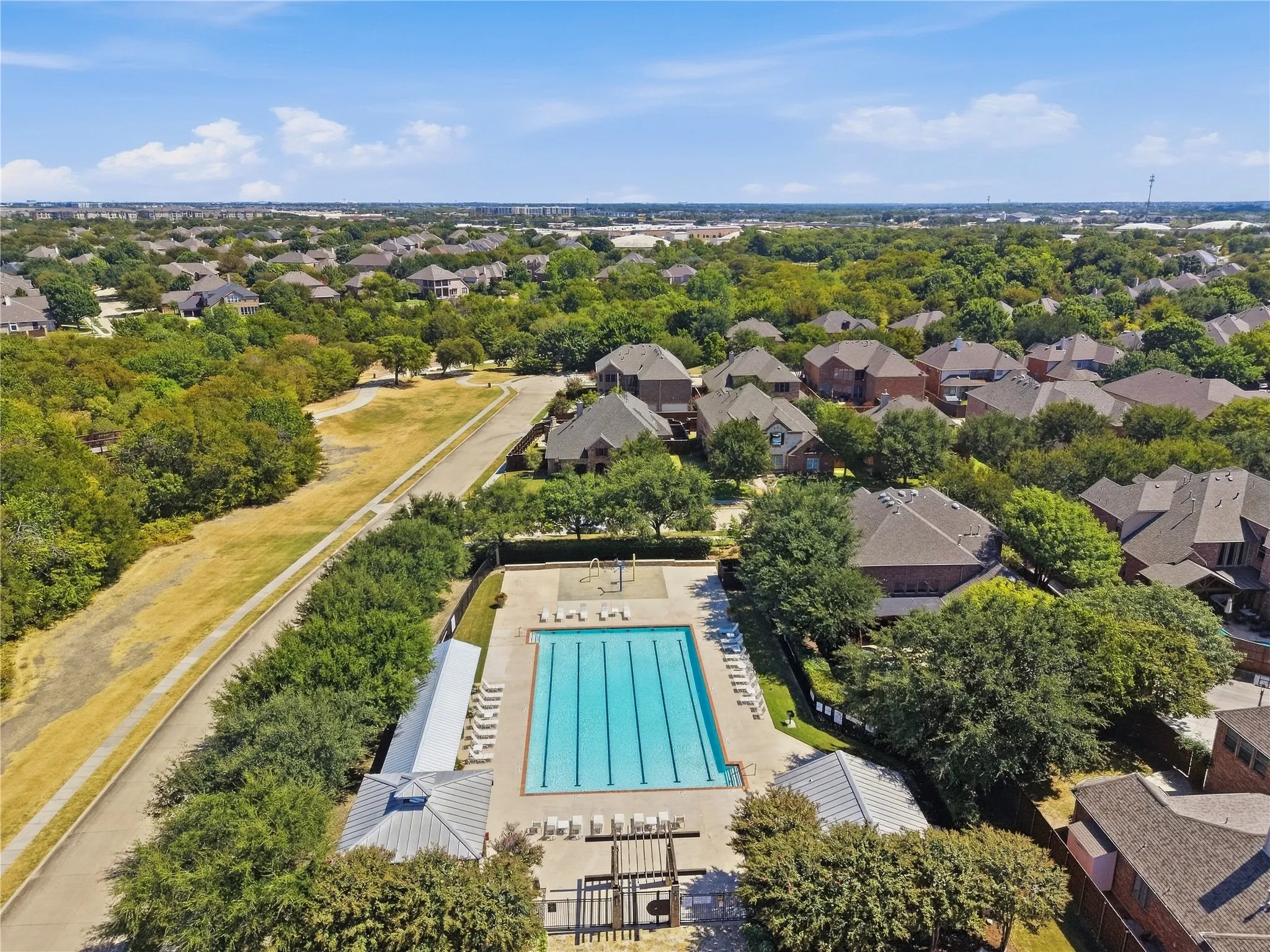 Community swimming pool with lap lanes, adjacent covered seating areas, and surrounding lounge chairs