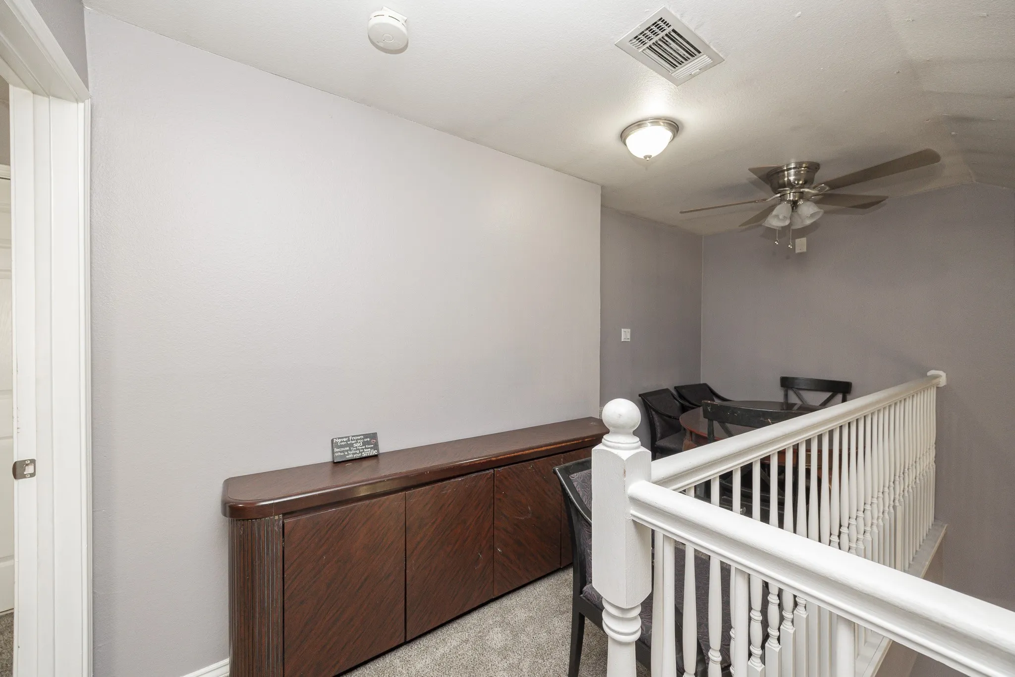 Wood-finish built-in cabinetry, white painted railing, ceiling fan with brushed nickel finish, recessed ceiling light