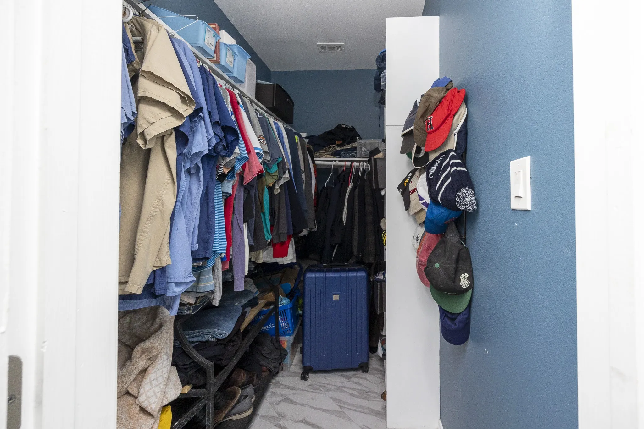 Custom closet featuring built-in shelving, multiple hanging rods, and a light-toned flooring