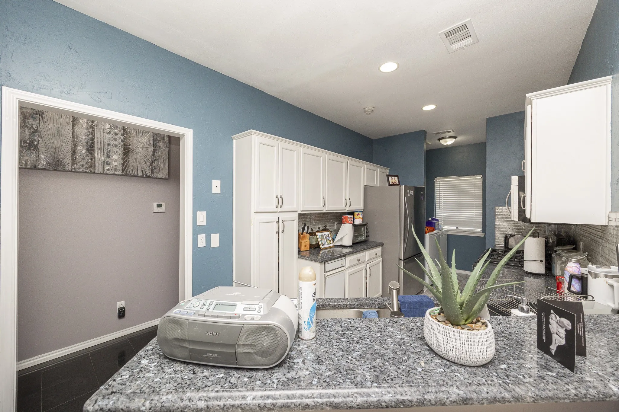 Kitchen featuring white cabinetry, stainless steel appliances, recessed lighting, and stone countertops