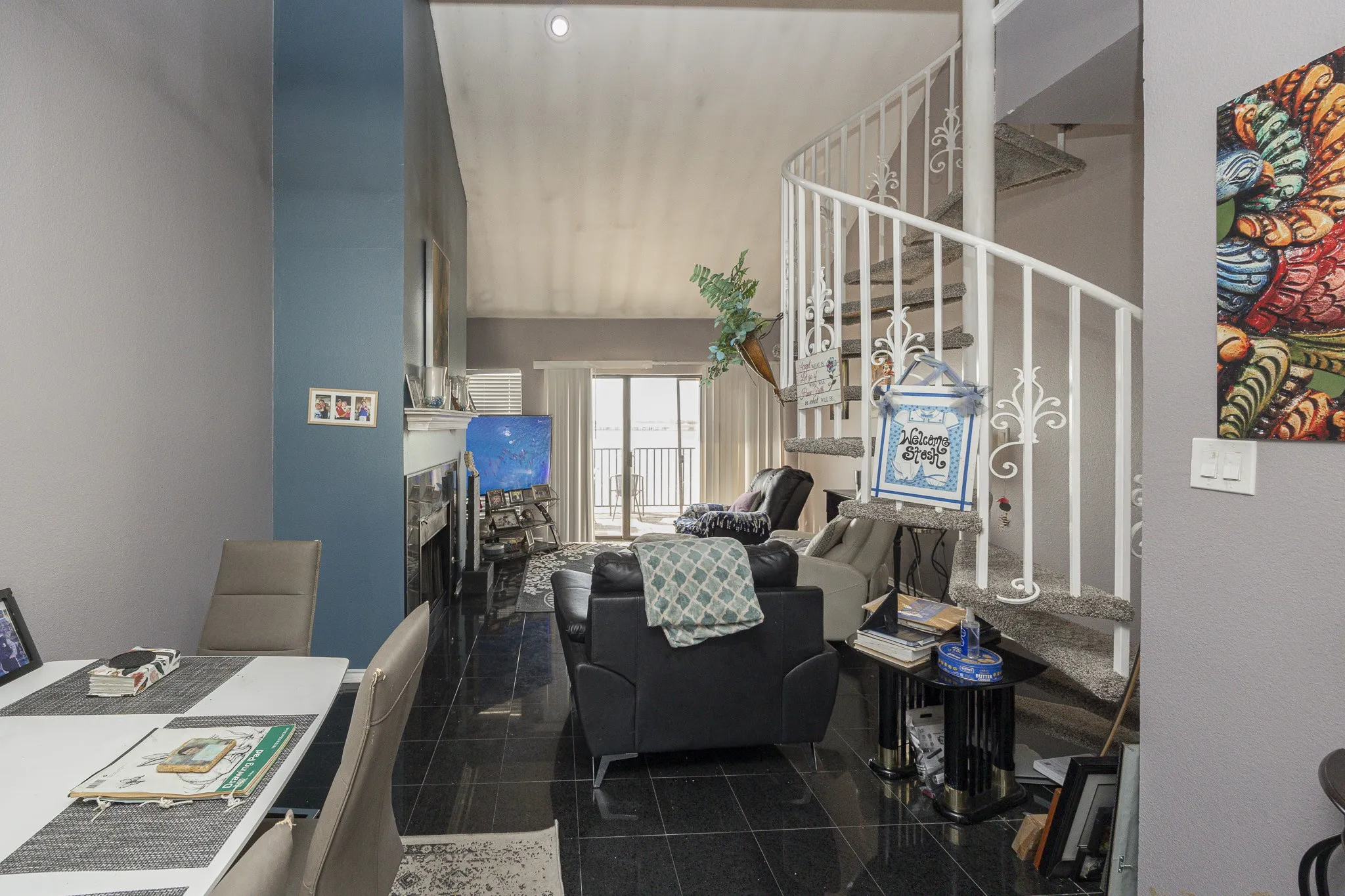 Vaulted ceilings above a living area with a fireplace, spiral staircase, and dark tile flooring