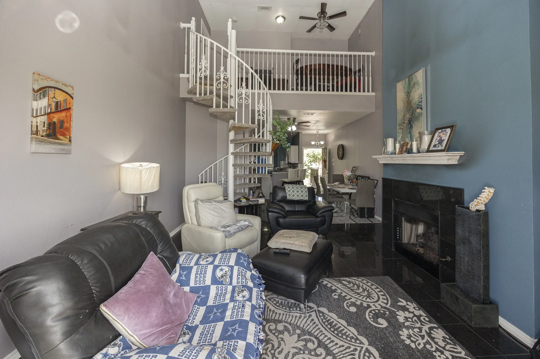 Two-story living area with a spiral staircase, an open-concept loft, a built-in fireplace with a mantel, and dark tile flooring