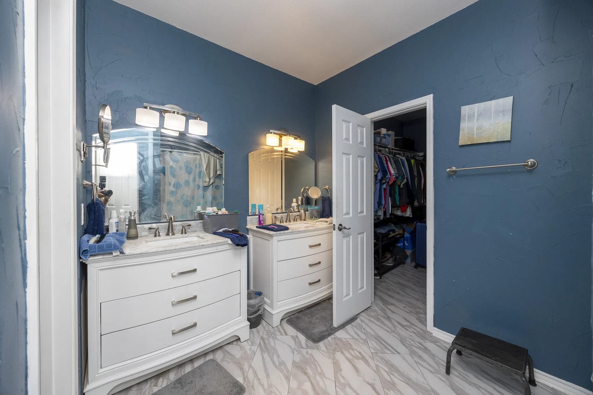 Dual sink vanity with white cabinetry and chrome hardware, complete with light-colored countertops