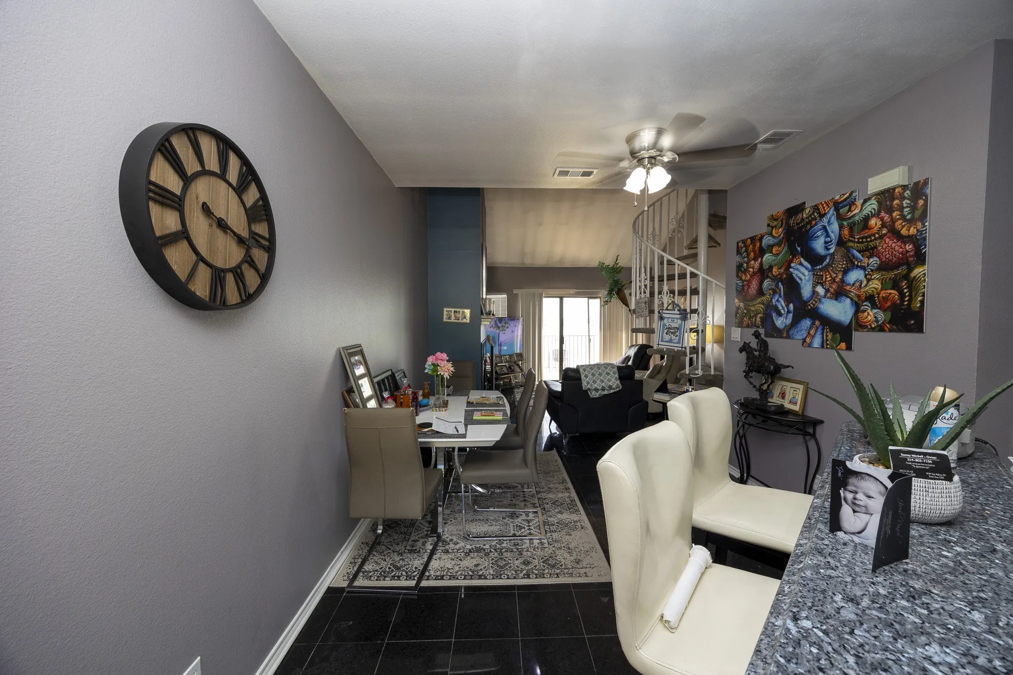 Black tile flooring, spiral staircase, ceiling fan, and sliding glass doors